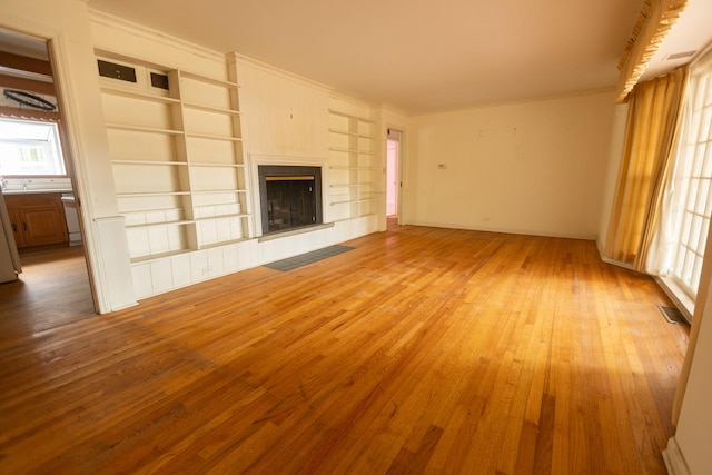 unfurnished living room with crown molding and light wood-type flooring