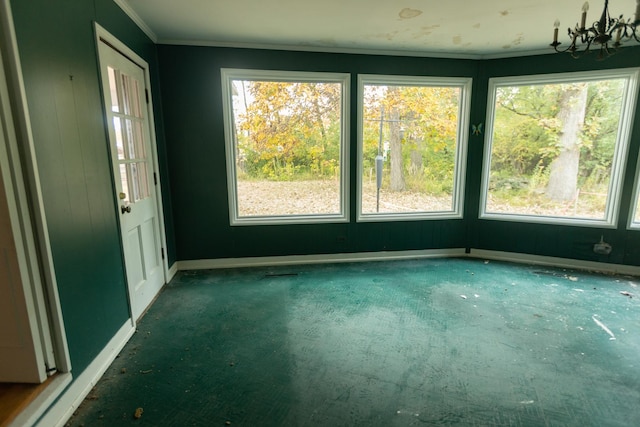 carpeted empty room featuring crown molding and an inviting chandelier