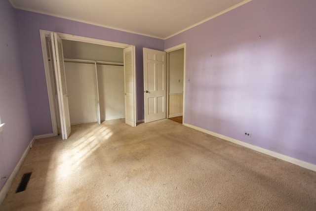 unfurnished bedroom with light carpet, crown molding, and a closet