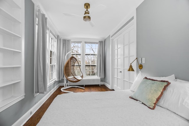 bedroom with dark wood-style floors, ceiling fan, baseboards, and radiator