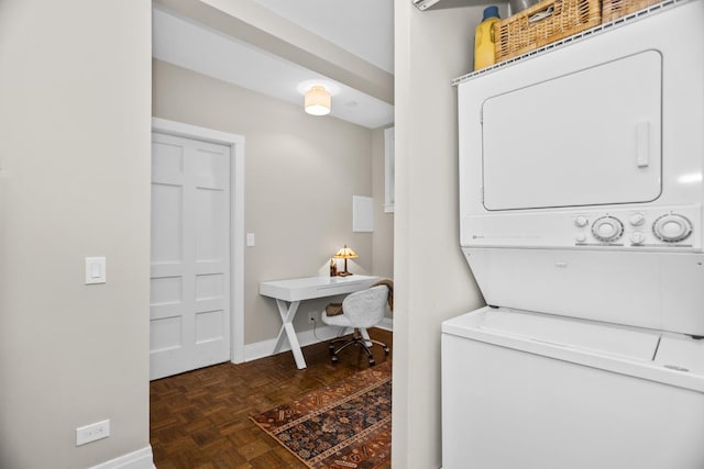 washroom featuring stacked washer and dryer, laundry area, and baseboards