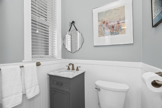 bathroom with toilet, a wainscoted wall, and vanity