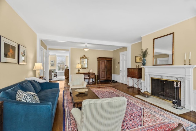 living area featuring ornamental molding, wood finished floors, and a high end fireplace