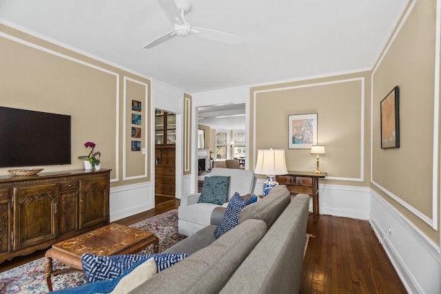 living room featuring dark wood-type flooring, a fireplace, baseboards, and ceiling fan