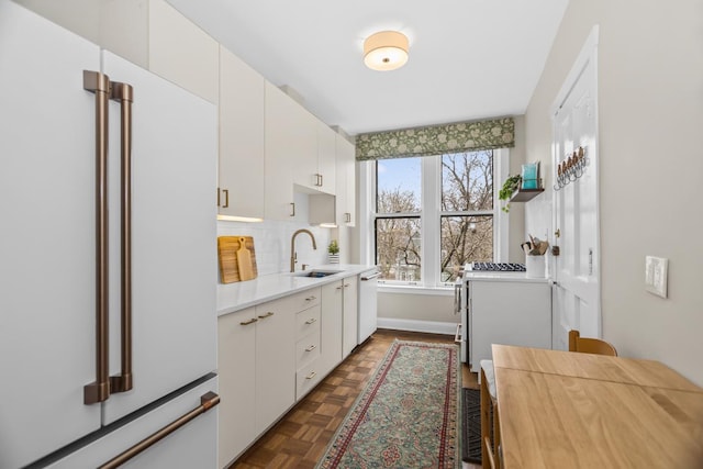 kitchen featuring light countertops, backsplash, white cabinetry, a sink, and white appliances