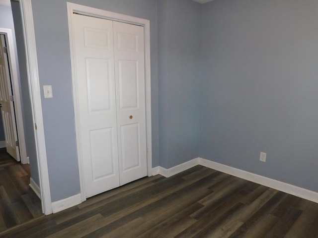 unfurnished bedroom with dark hardwood / wood-style flooring and a closet