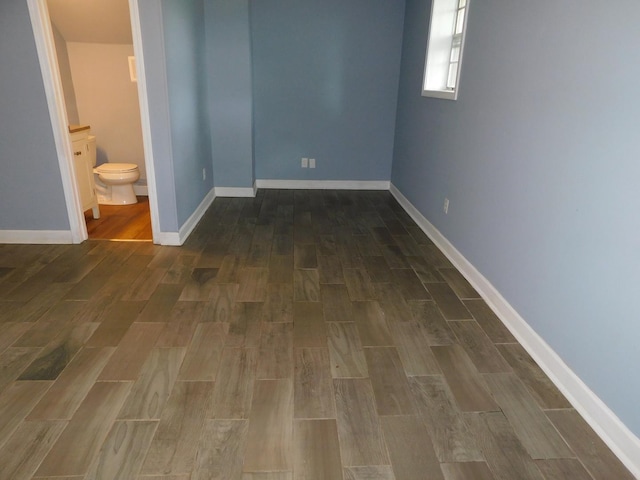 unfurnished bedroom featuring dark wood-type flooring and ensuite bath