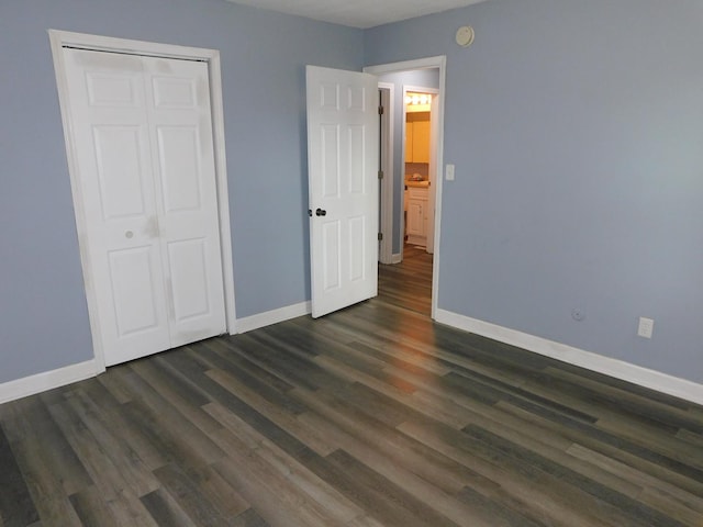 unfurnished bedroom with dark hardwood / wood-style flooring and a closet