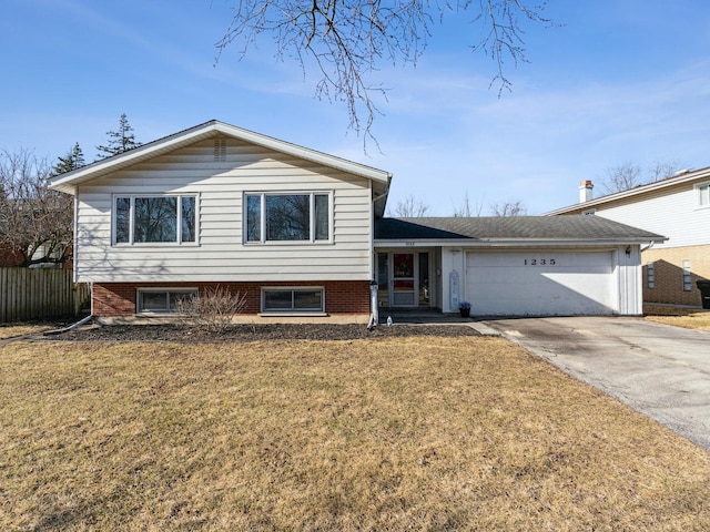 split level home featuring fence, driveway, a front lawn, a garage, and brick siding