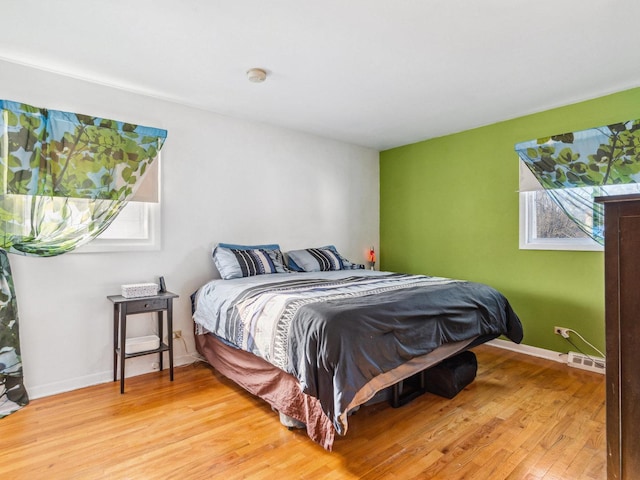 bedroom with visible vents, baseboards, and light wood finished floors