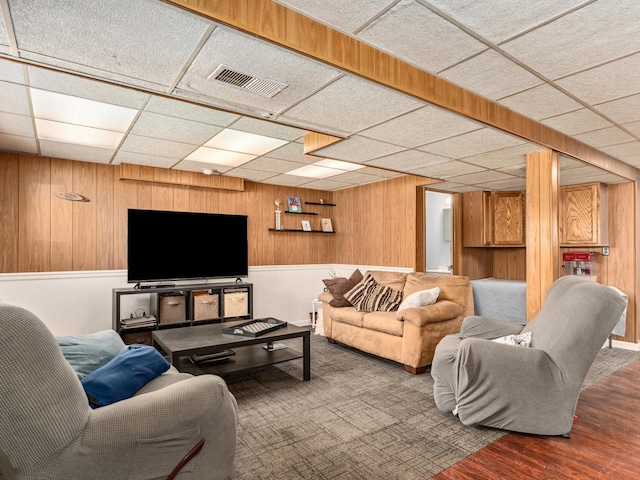 living room with visible vents, wood walls, and wood finished floors