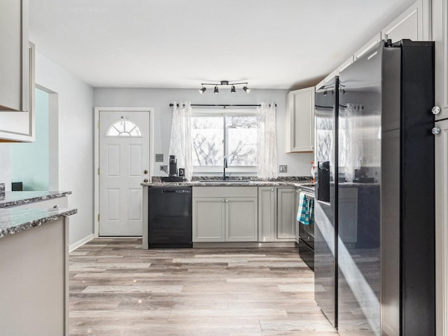 kitchen with light wood-type flooring, stainless steel refrigerator with ice dispenser, a sink, stone countertops, and dishwasher