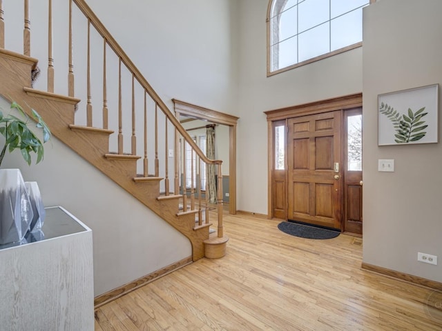 foyer entrance with stairs, a healthy amount of sunlight, a high ceiling, and wood finished floors