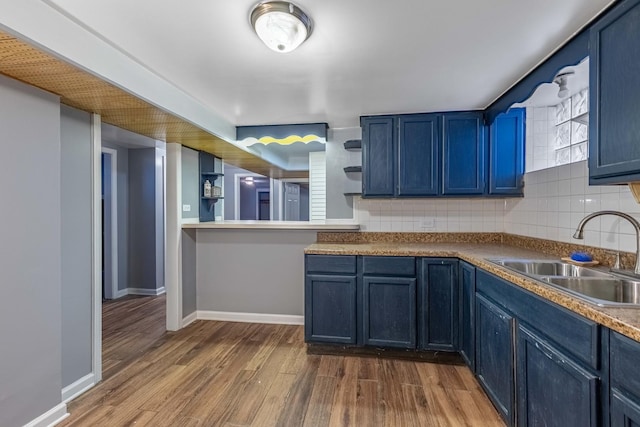 kitchen with sink, decorative backsplash, wood-type flooring, and blue cabinets