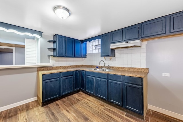 kitchen with tasteful backsplash, sink, wood-type flooring, and blue cabinetry