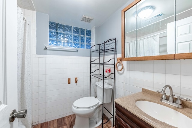 bathroom with hardwood / wood-style floors, vanity, tile walls, and toilet