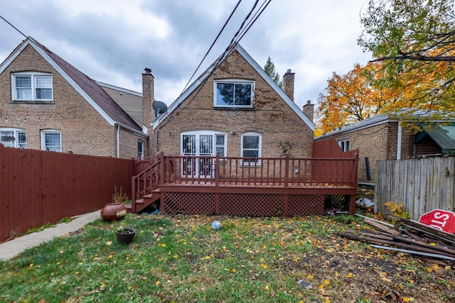 back of property featuring a wooden deck and a lawn