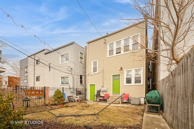 rear view of house with entry steps, central AC unit, and a fenced backyard