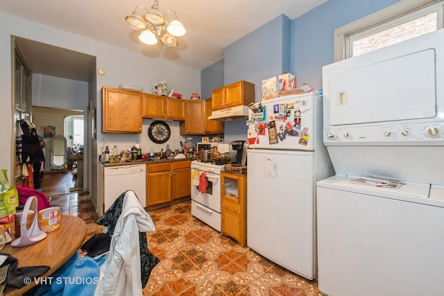 kitchen featuring a notable chandelier, under cabinet range hood, white appliances, a sink, and stacked washer / drying machine