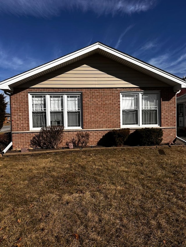 view of property exterior featuring brick siding and a lawn