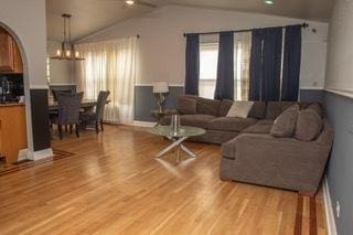 living room featuring vaulted ceiling, a notable chandelier, and light wood-type flooring