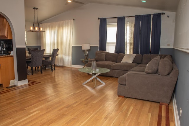 living room featuring vaulted ceiling, a healthy amount of sunlight, a chandelier, and light wood-style floors