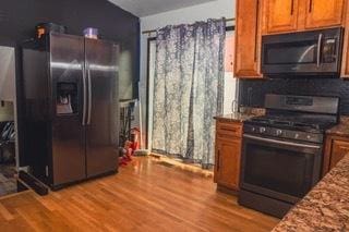 kitchen with stainless steel appliances, stone counters, and light wood-type flooring