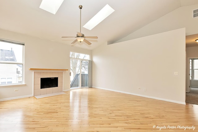 unfurnished living room with a ceiling fan, light wood-style flooring, a healthy amount of sunlight, and a skylight