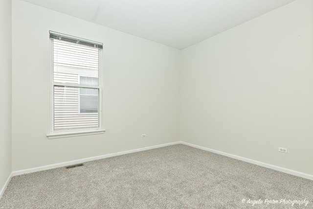 carpeted empty room featuring baseboards and visible vents