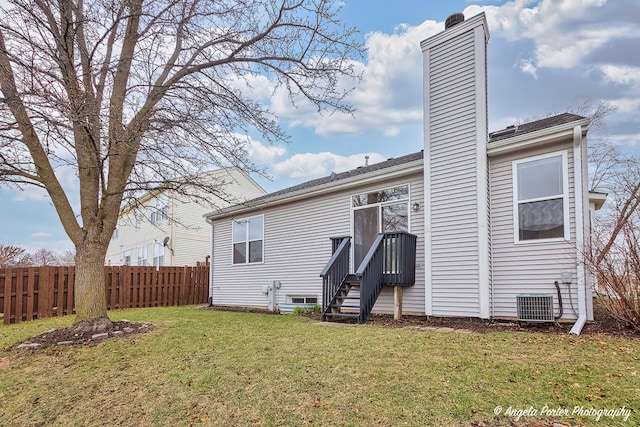 back of house featuring a chimney, cooling unit, fence, and a yard