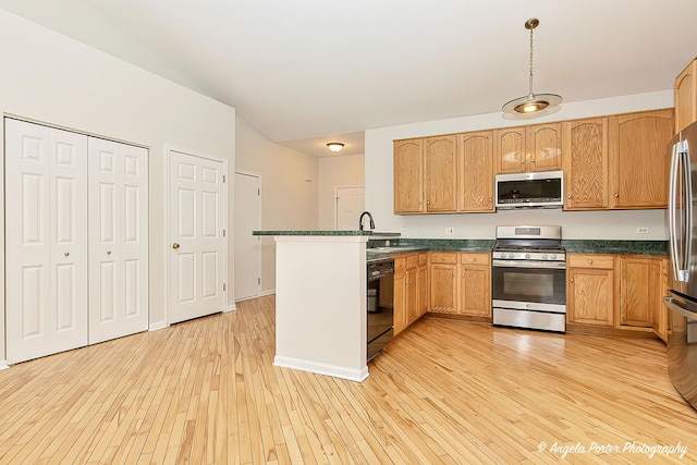 kitchen with a sink, a peninsula, light wood-type flooring, stainless steel appliances, and dark countertops