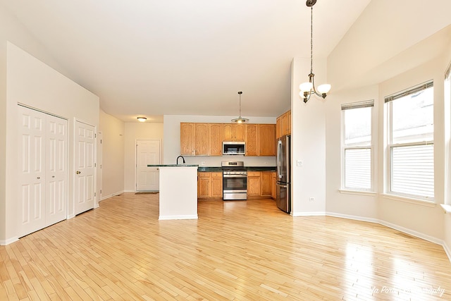kitchen featuring baseboards, stainless steel appliances, dark countertops, light wood-type flooring, and an inviting chandelier