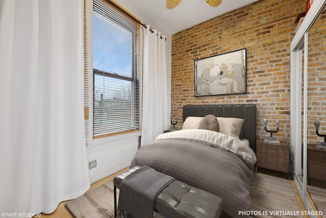 bedroom with brick wall, baseboards, and wood finished floors