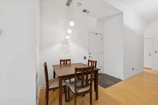 dining room with baseboards, visible vents, and wood finished floors