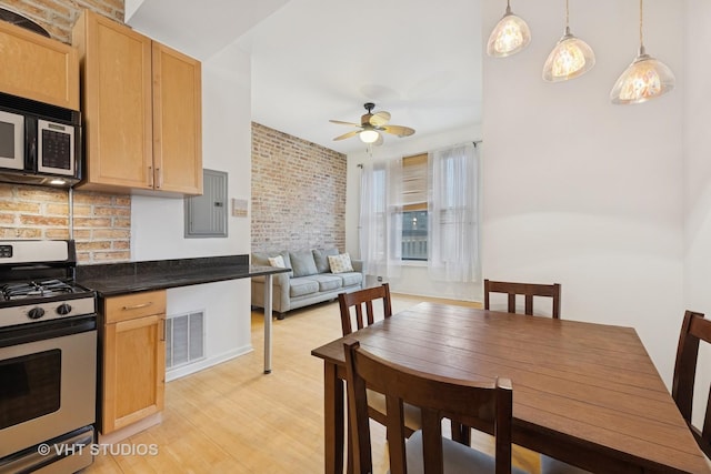 kitchen with stainless steel gas range oven, light wood-style flooring, visible vents, electric panel, and dark countertops