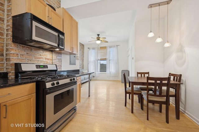 kitchen featuring stainless steel gas stove, decorative backsplash, a ceiling fan, hanging light fixtures, and light wood-type flooring