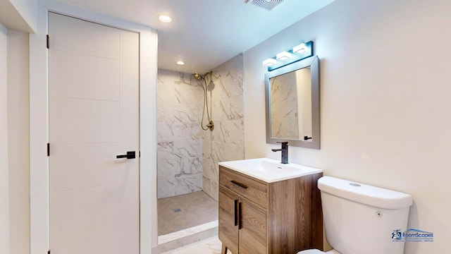 bathroom featuring vanity, toilet, and a tile shower