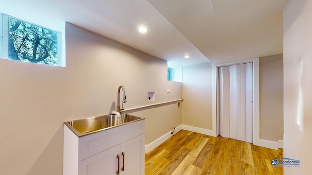 bar featuring white cabinetry, a wealth of natural light, sink, and light wood-type flooring