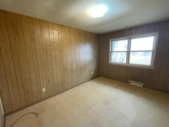 empty room featuring wood walls and visible vents