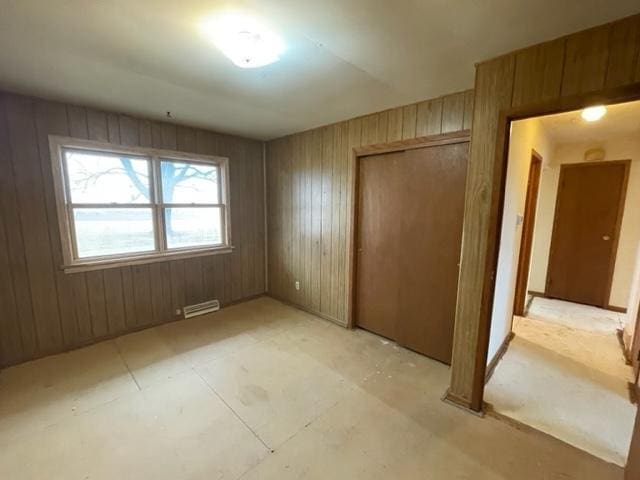 unfurnished bedroom with a closet, visible vents, and wood walls