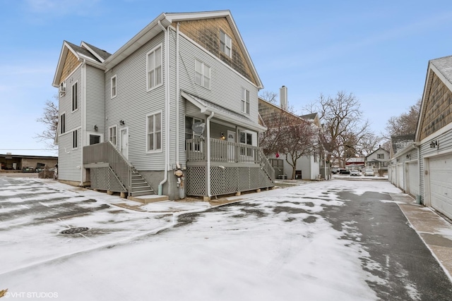 snow covered property featuring a garage and covered porch