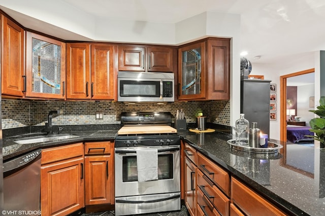 kitchen with dark stone countertops, sink, decorative backsplash, and stainless steel appliances