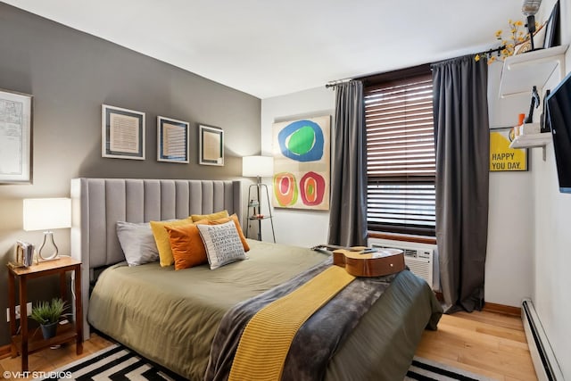 bedroom featuring a baseboard radiator, cooling unit, and light hardwood / wood-style flooring