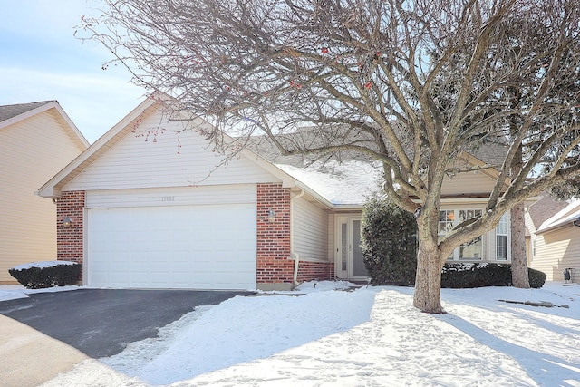 single story home featuring a garage, brick siding, and aphalt driveway