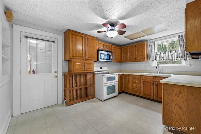 kitchen featuring tasteful backsplash, ceiling fan, sink, and range with two ovens