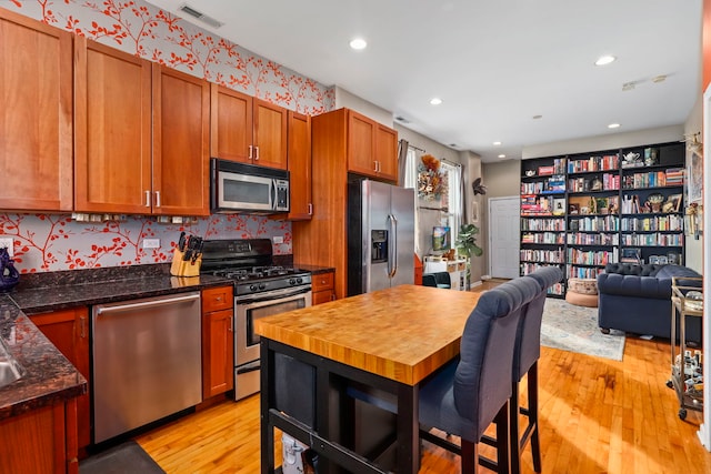 kitchen with dark countertops, visible vents, appliances with stainless steel finishes, and open floor plan