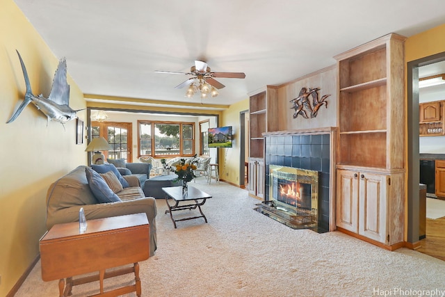 carpeted living room with a tile fireplace and ceiling fan