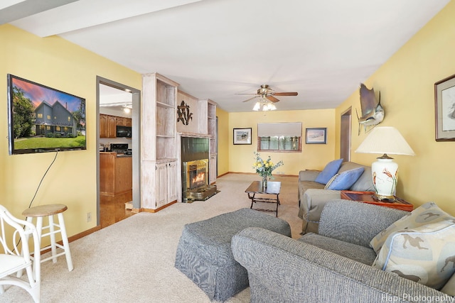 living room with ceiling fan, light colored carpet, and a tiled fireplace