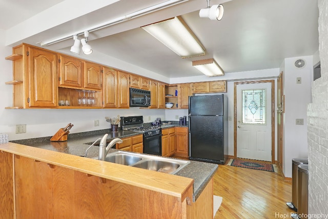 kitchen featuring sink, light hardwood / wood-style flooring, track lighting, kitchen peninsula, and black appliances