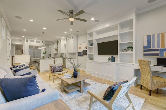 living room with light wood-type flooring, built in desk, crown molding, and ceiling fan